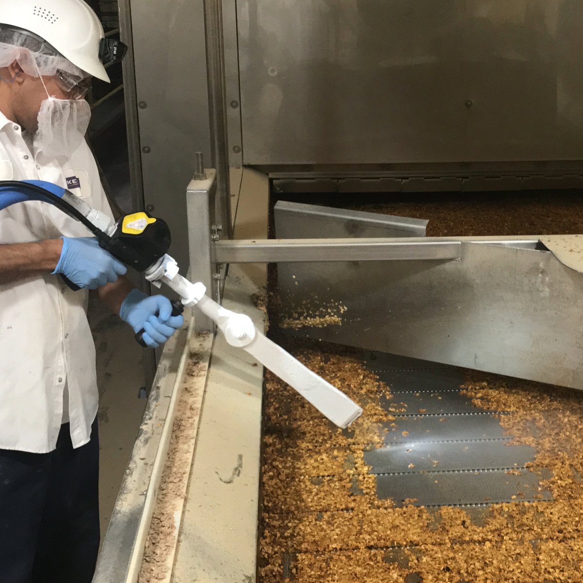 Dry ice blasting cleaning sugary buildup and granola from oven belt